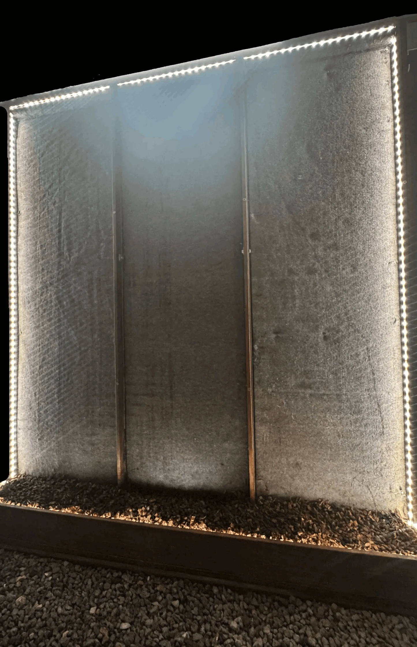 A green living wall installation with illuminated edges, featuring a textured felt surface and a gravel base.